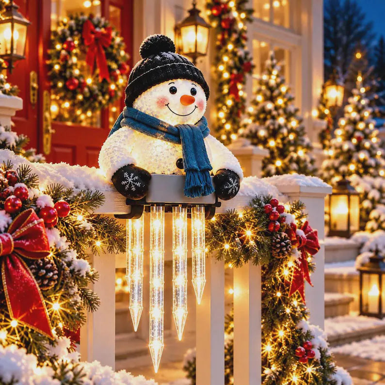 Snowman on a snowy front porch beside a red door